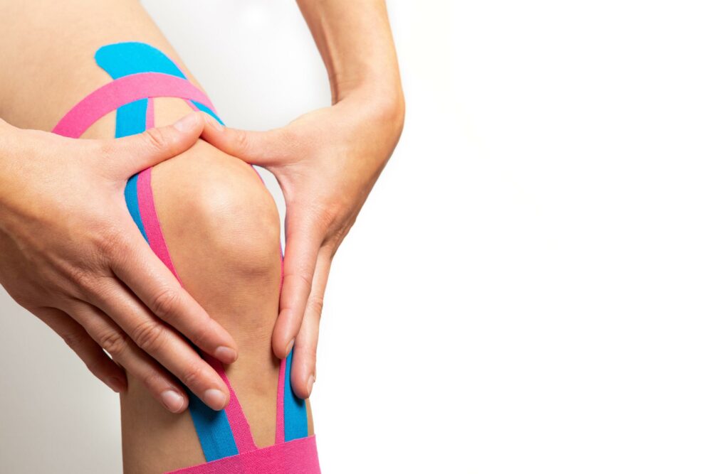 Kinesiotaping, kinesiology. Female athlete with kinesiotape, muscle tape on knee